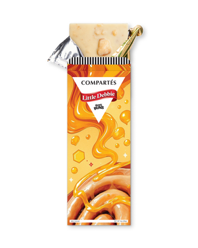 A partially unwrapped Compartés Little Debbie Honey Buns chocolate bar, showing the creamy beige chocolate filling and a gold foil seal, set against a plain white background.